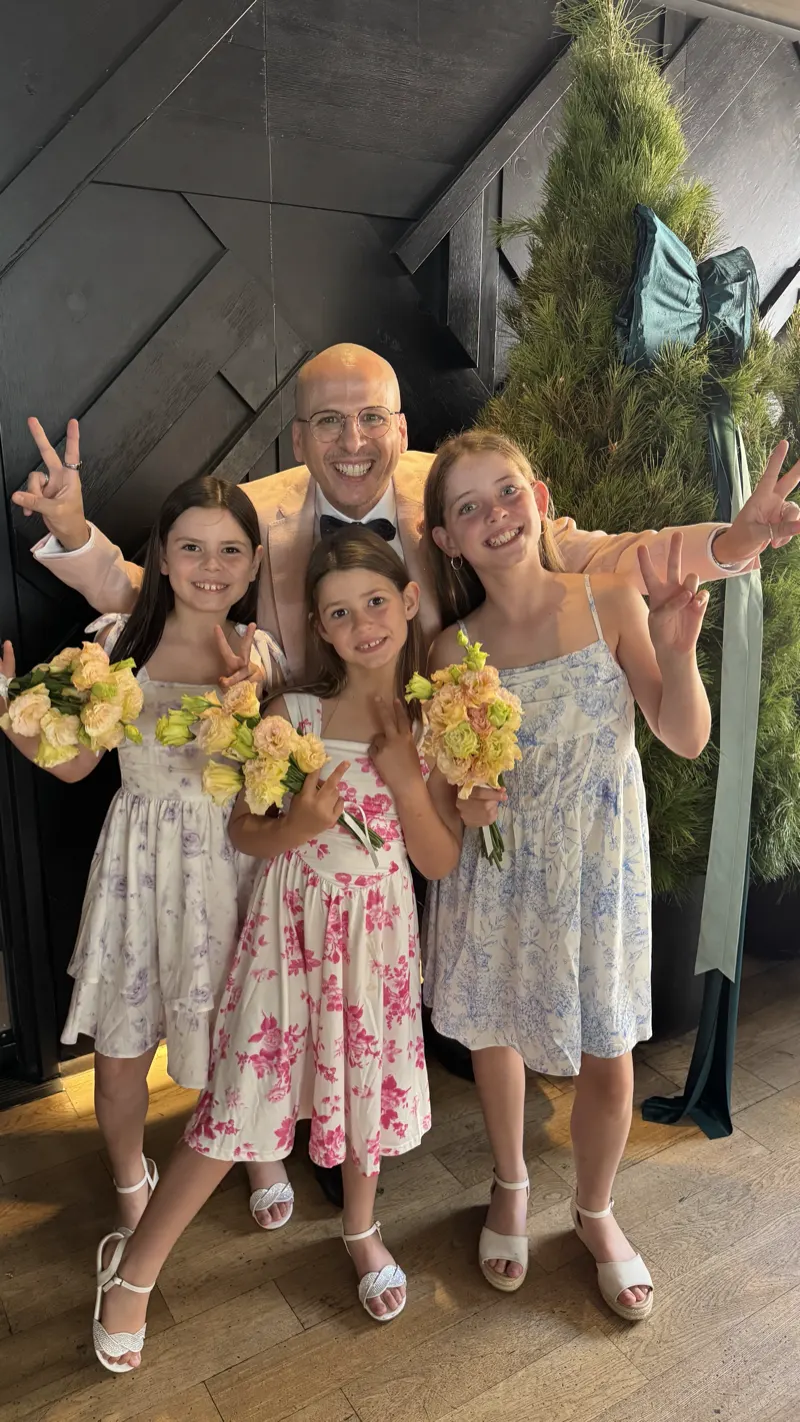 Andrés celebrating with three young flower girls holding their bouquets